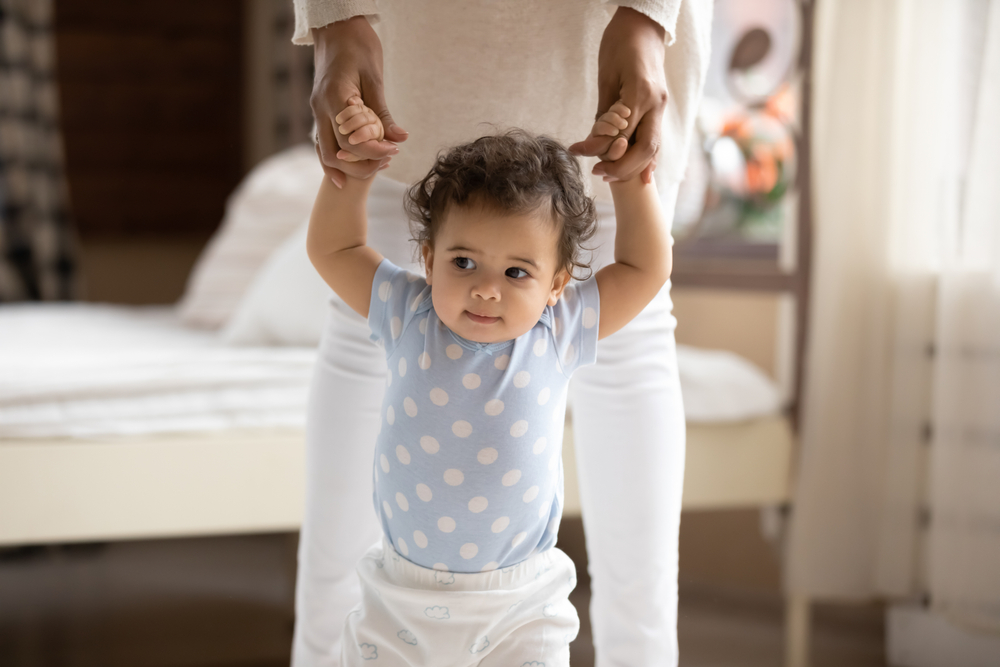 baby holding mums hands and walking 